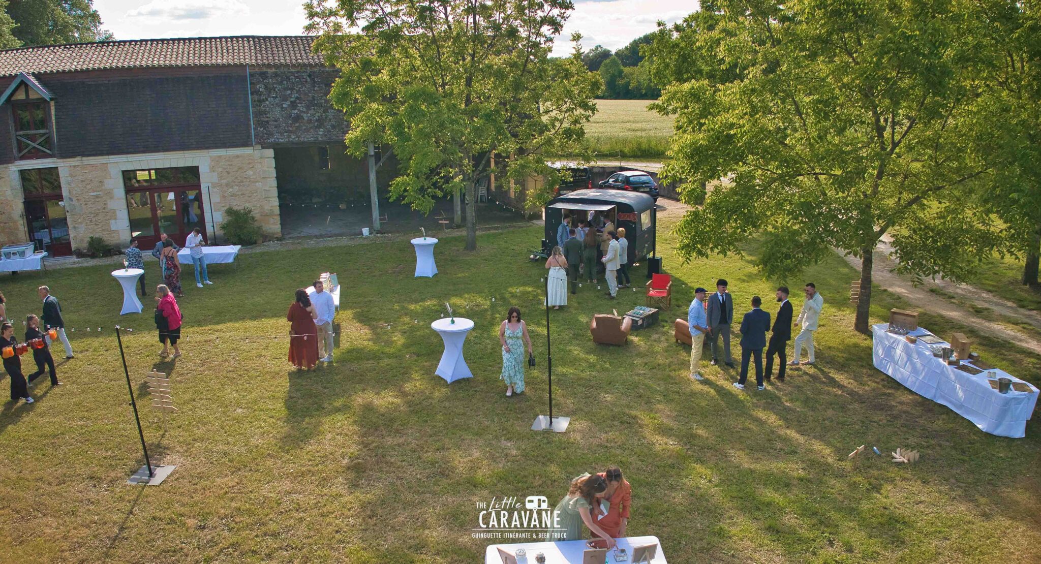 Caravane vintage aménagée en bar à vinyles et bar à bières pour mariage, installée en extérieur dans une ambiance guinguette.