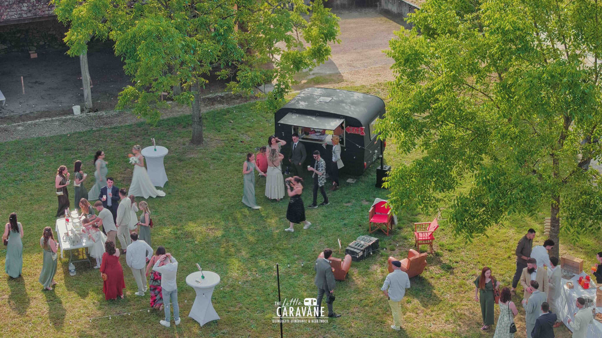 Caravane vintage aménagée en bar à vinyles et bar à bières pour mariage, installée en extérieur dans une ambiance guinguette.