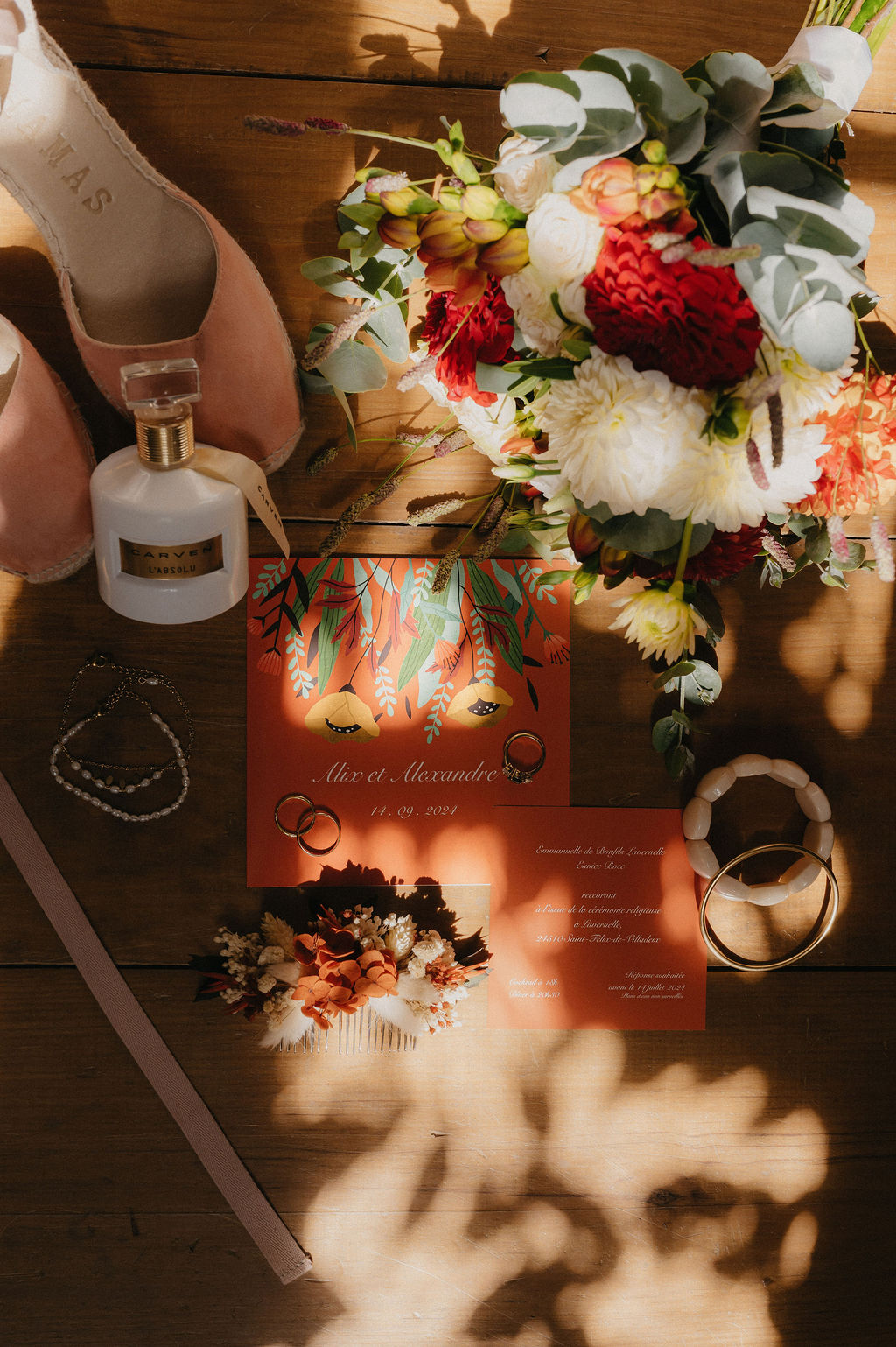 flat lay avec le bouquet de la mariée, la papeterie, le parfum de la mariée et ses accessoires