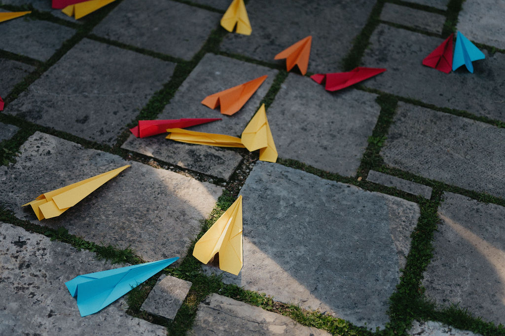 avions en papier de couleur lancés à la sortie de l'église sur les jeunes mariés