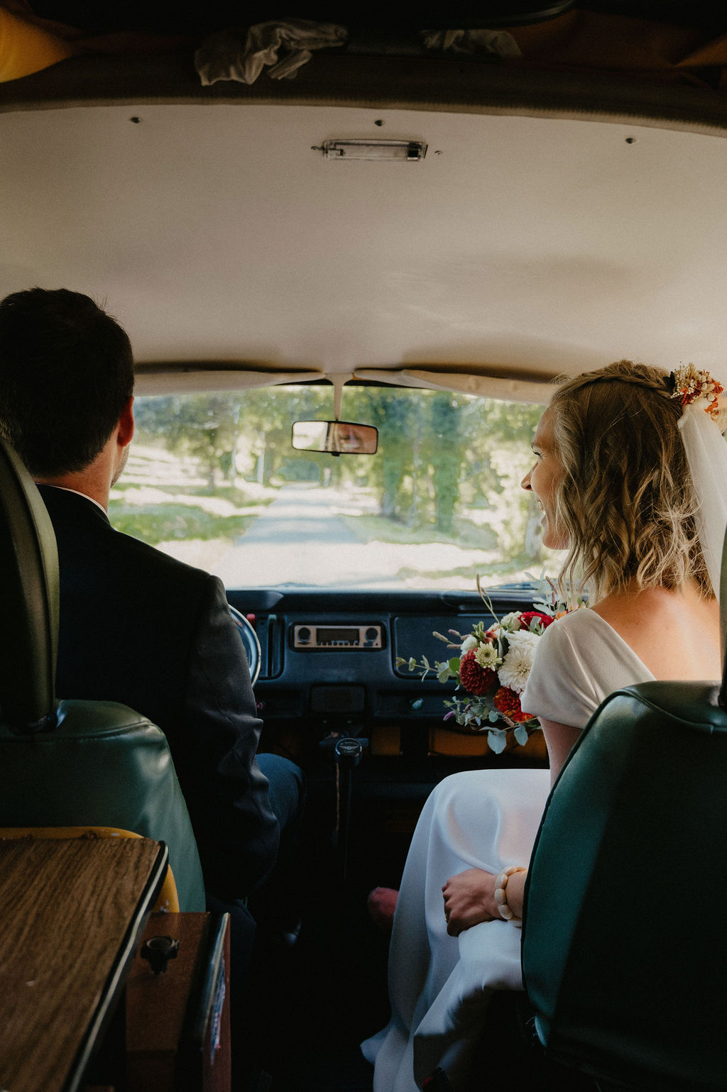 couple de jeune mariés revenant de l'égliqe dans un van vintage loué pour l'occasion