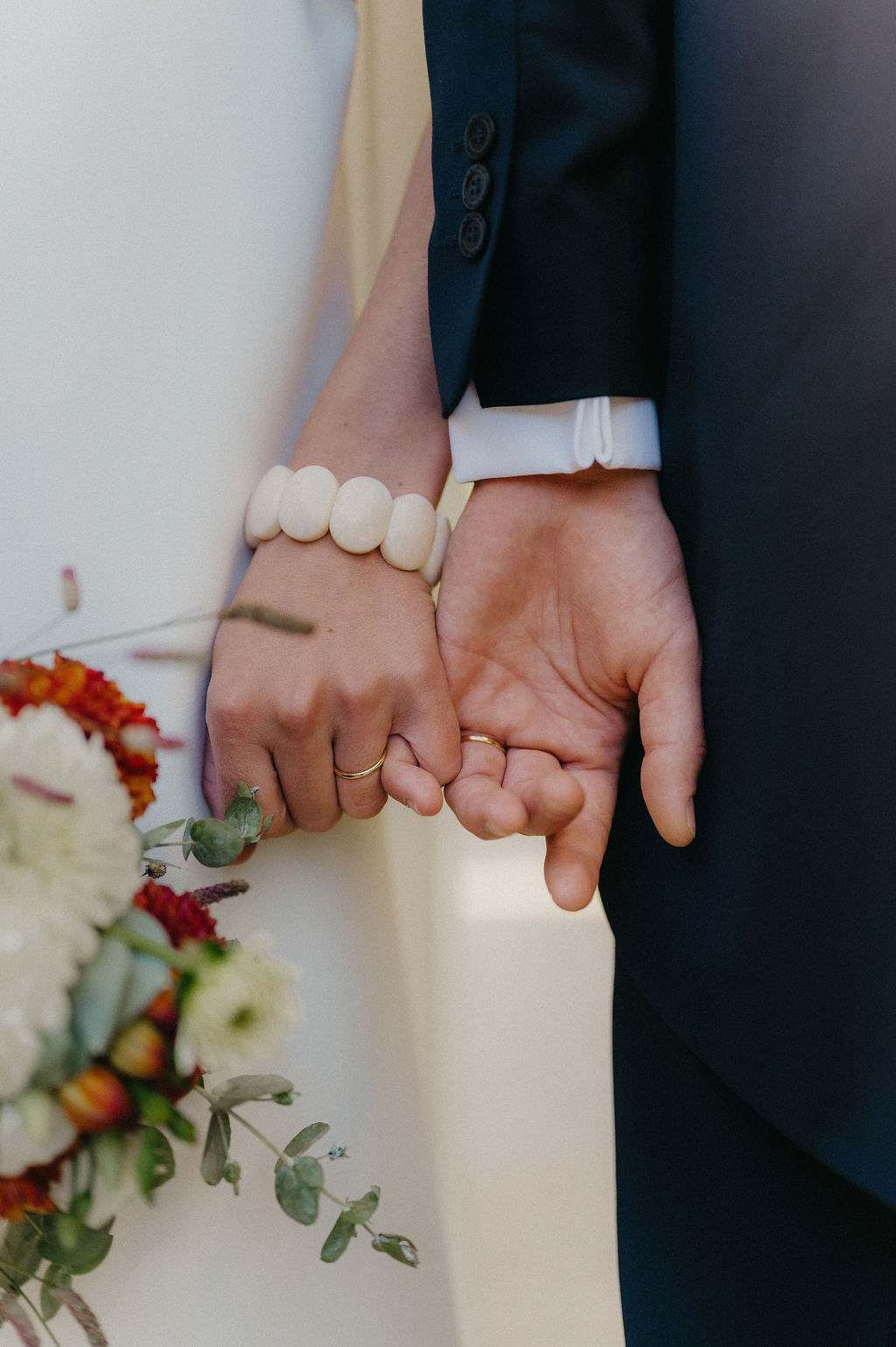photo de details de mains de jeunes mariés avec bracelet et fleurs