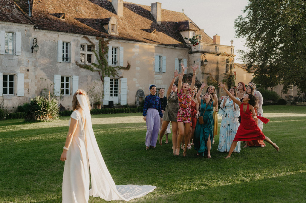 une mariée s'apprete à lancer son bouquet aux jeunes filles lors du cocktail du mariage