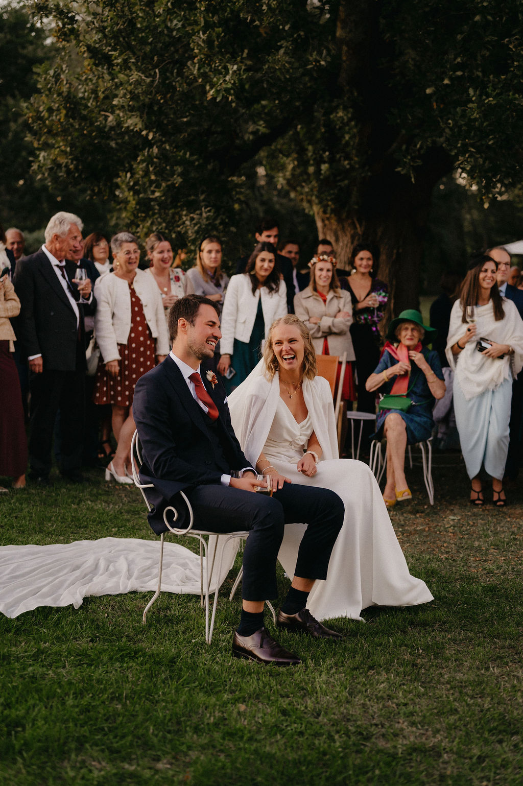 couple de marié riant en ecoutant le discours preparé par leur proches lors du cocktail de leur mariage