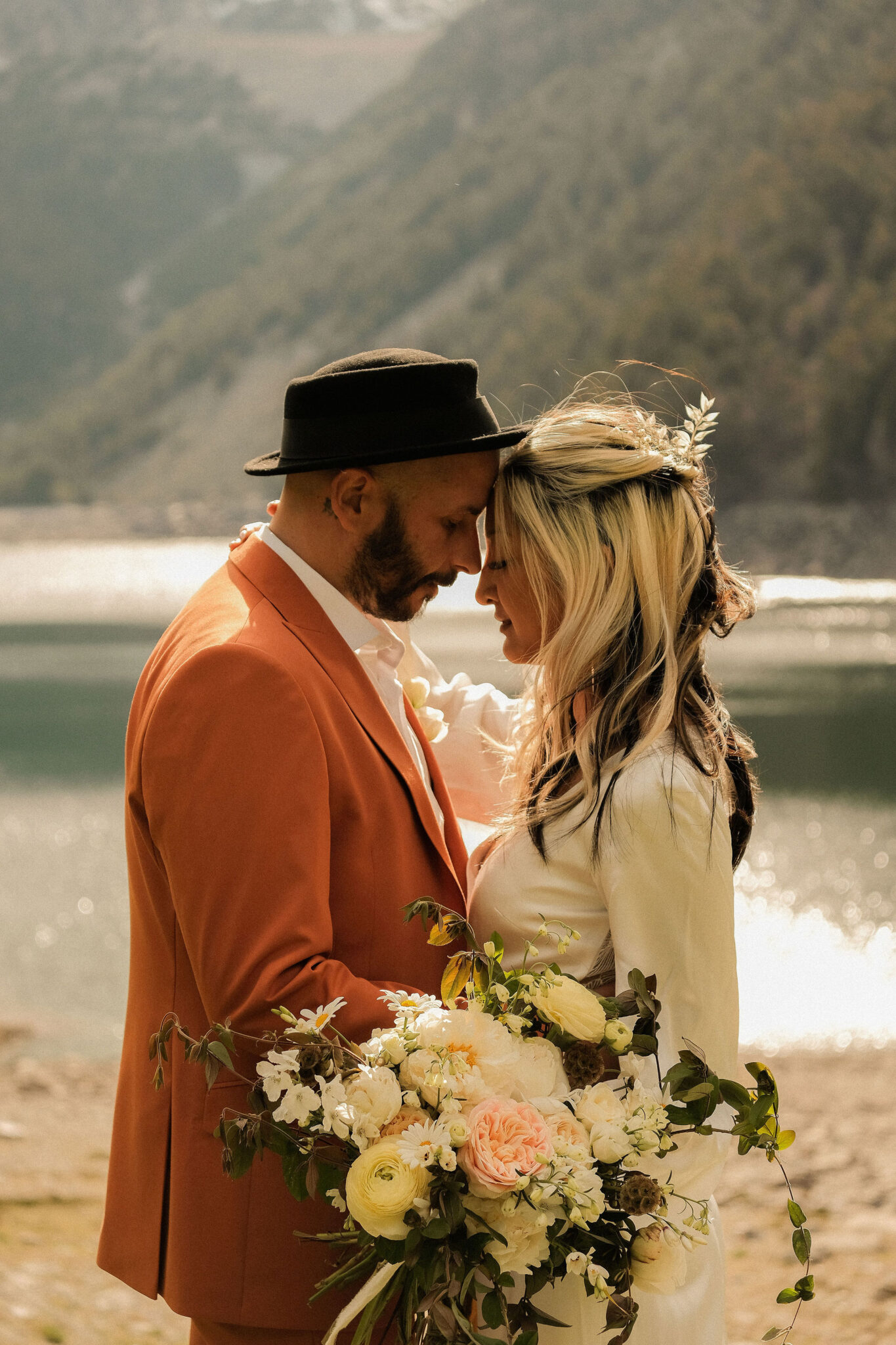 Couple lors d'une cérémonie laique au bord d'un lac avec le marié en costume terra cota loué pour le mariage