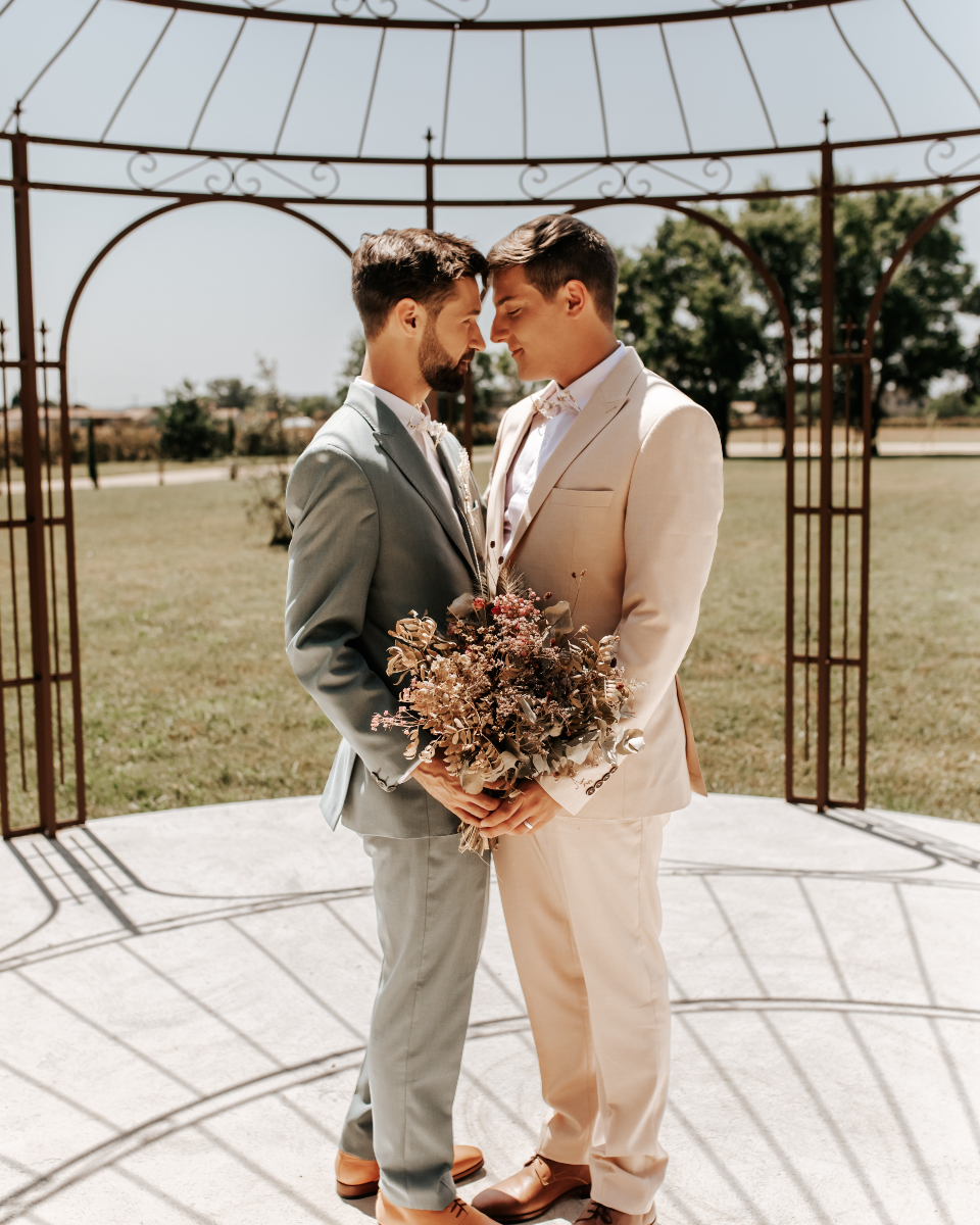 couple gay de jeunes mariés portant des costumes vert olive et beige de location