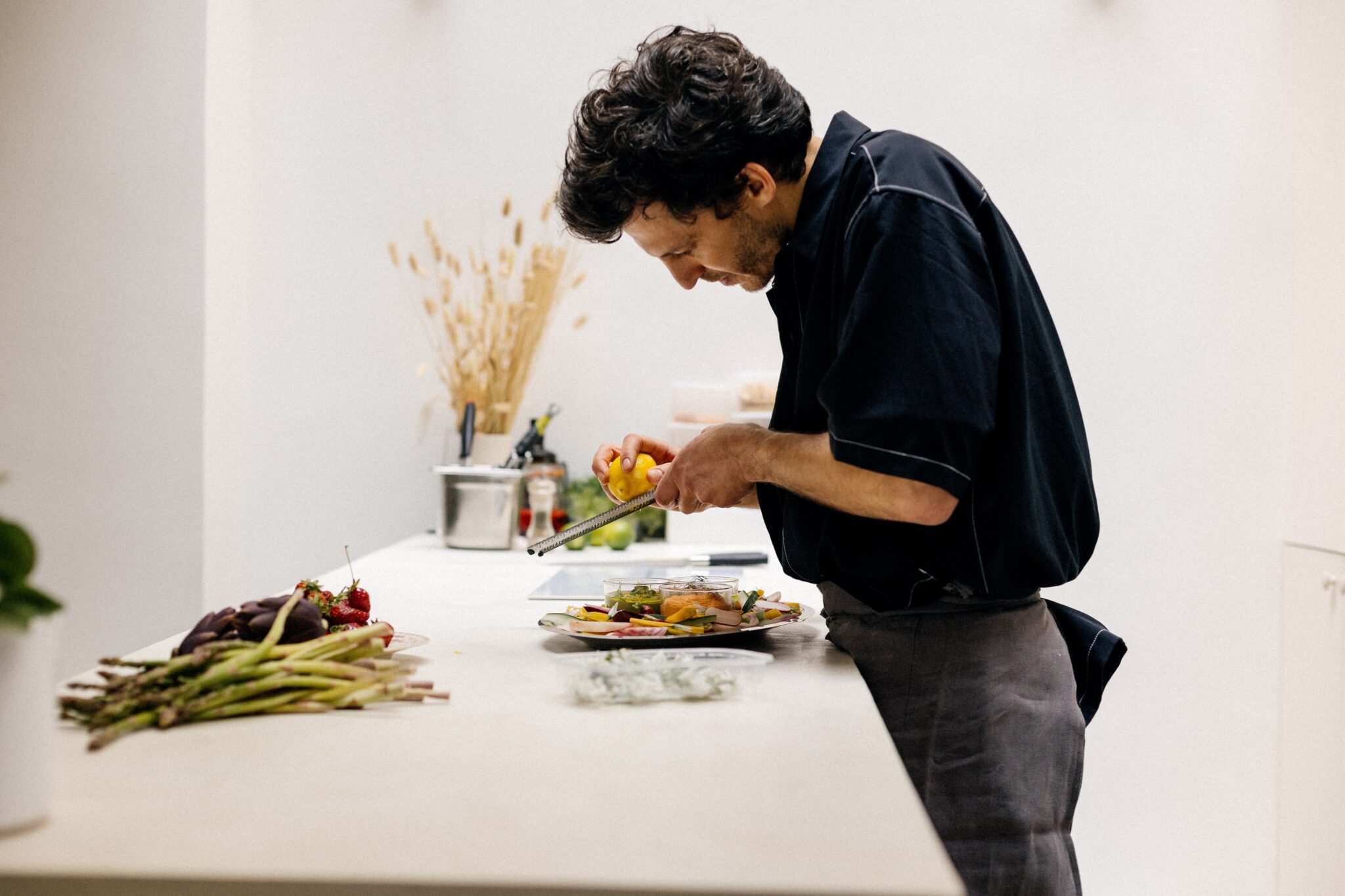 Traiteur souriant préparant des plats devant les invités lors d’un événement.