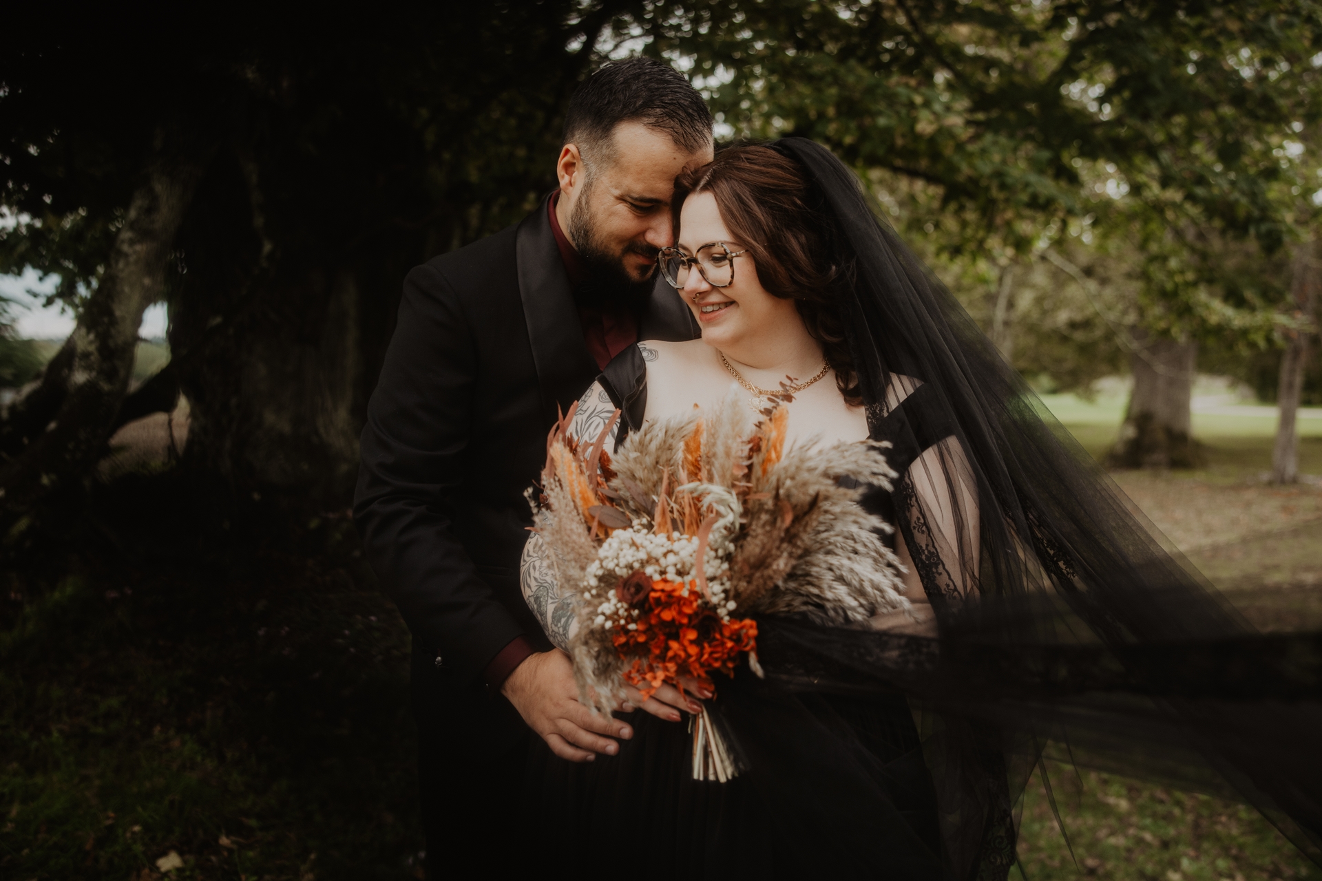 couple de mariés gothiques habillés de noir et bouquet de fleurs séchées